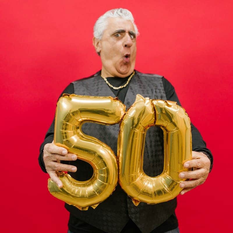 a man holding balloon shaped numbers fifty and zero