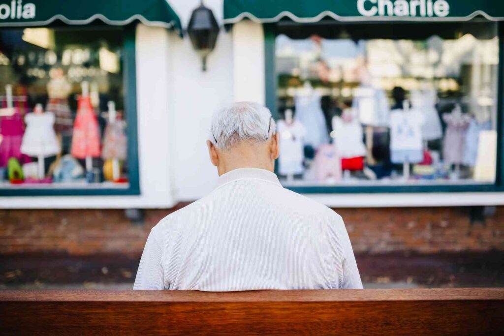 an old man sitting on a bench in front of a shop