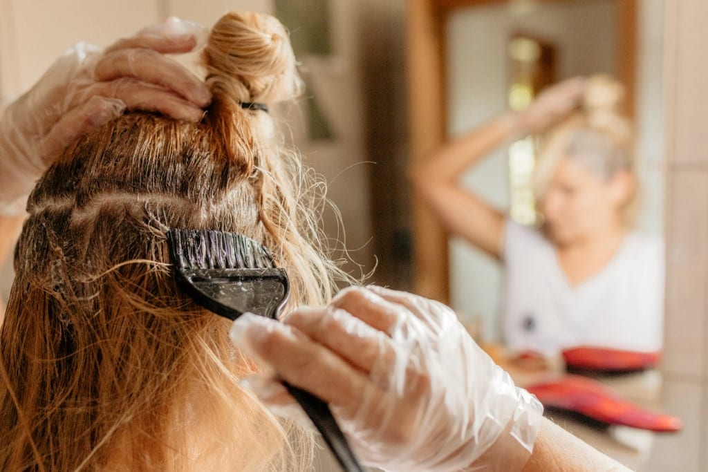 Rear view of woman dyeing hair in front of mirror
