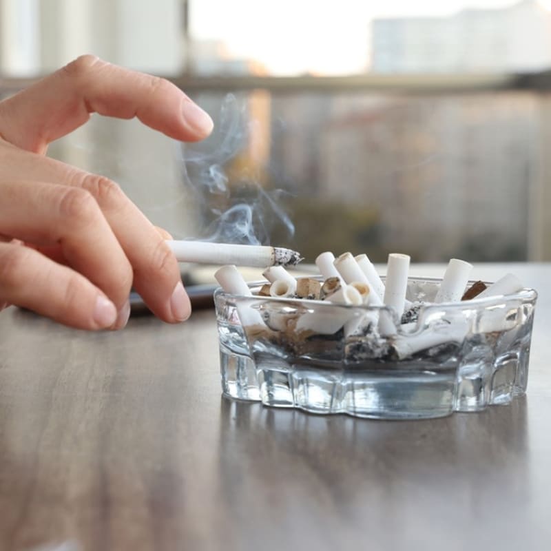 A hand holding a lit cigarette between fingers