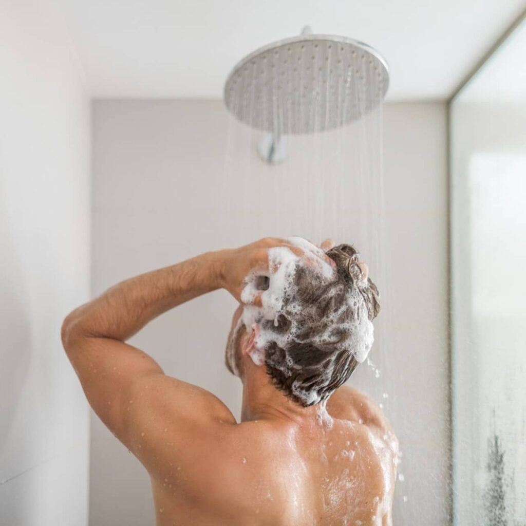 man washing his hair under a shower
